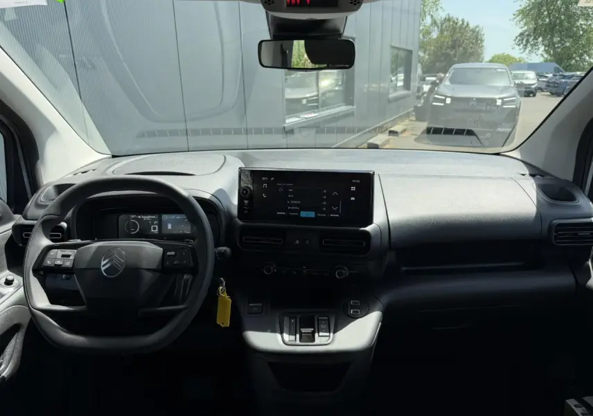Vue intérieure du tableau de bord du Citroën Berlingo ë-136 gris Artense, avec écran tactile central et volant multifonction.