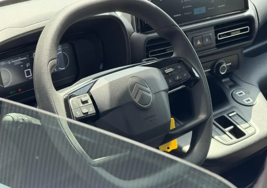 Vue rapprochée du volant et tableau de bord du Citroën Berlingo gris Artense avec écran tactile et commandes intégrées.