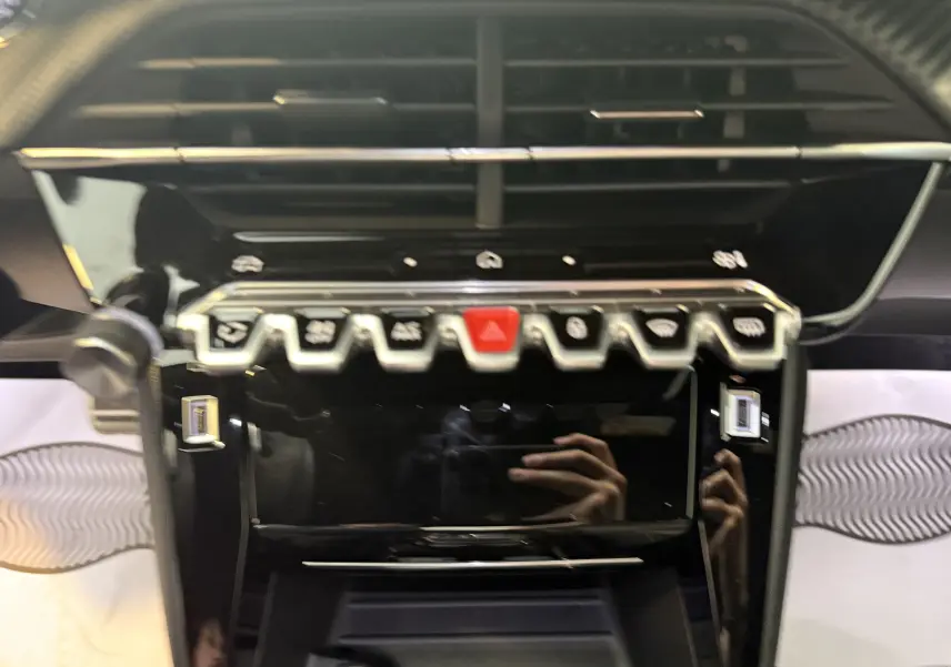 Vue rapprochée du tableau de bord noir brillant du Peugeot 2008 1.2 PureTech GT 2025 avec commandes tactiles et boutons métallisés.