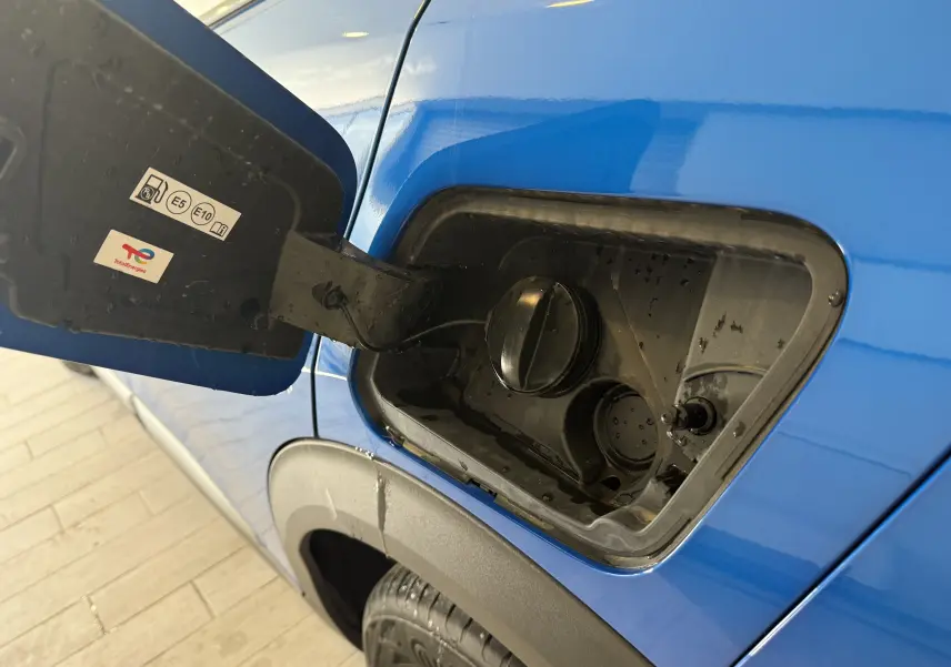Gros plan sur la trappe à carburant côté gauche d'un Peugeot 2008 bleu Vertigo métal avec toit noir, année 2025.