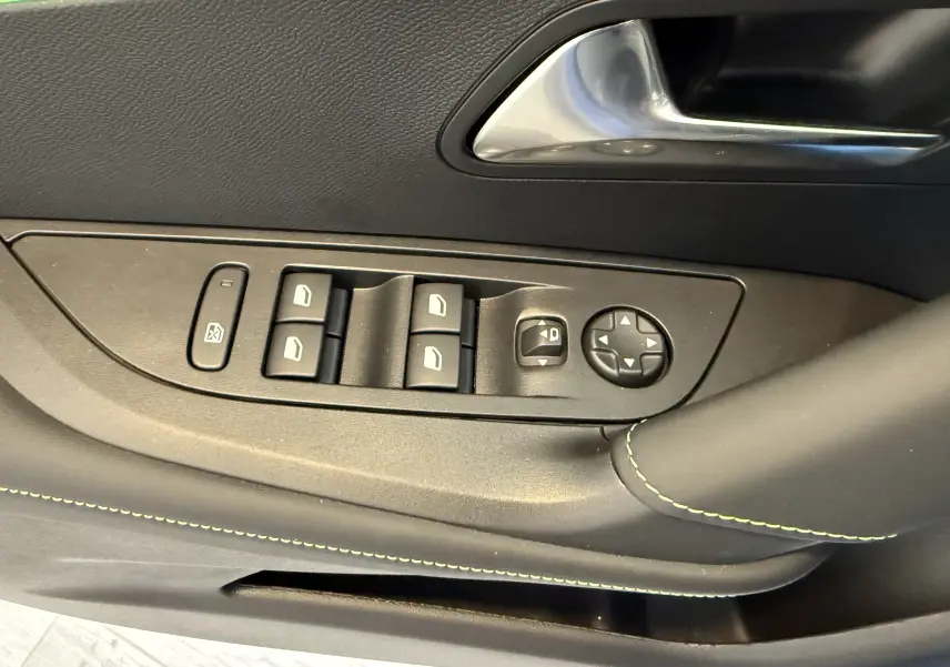 Gros plan sur la commande des vitres et rétroviseurs côté gauche du PEUGEOT 2008 GT avec surpiqûres vertes sur la porte noire.