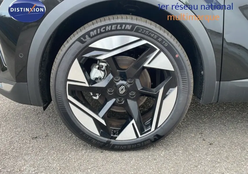 Gros plan sur la roue avant gauche d'une Renault Symbioz noire étoile métal avec jante bicolore stylisée.