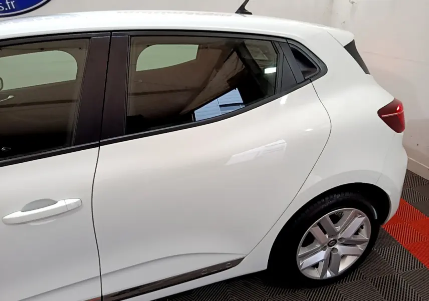 Vue latérale droite d'une Renault Clio Business TCe 90 blanche, mettant en valeur la porte arrière et la roue arrière.