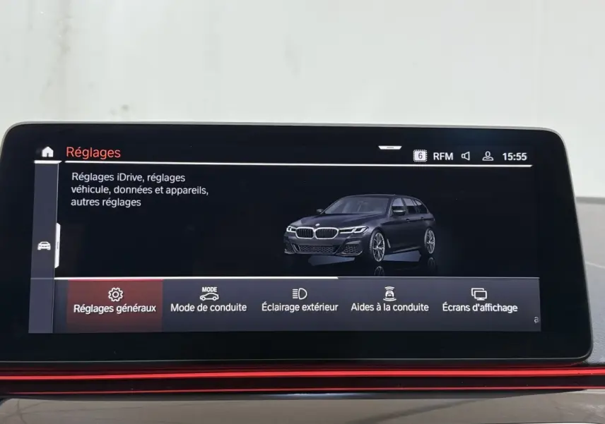 Écran tactile intérieur affichant une BMW Série 5 Touring noire en 3/4 avant dans le menu réglages.