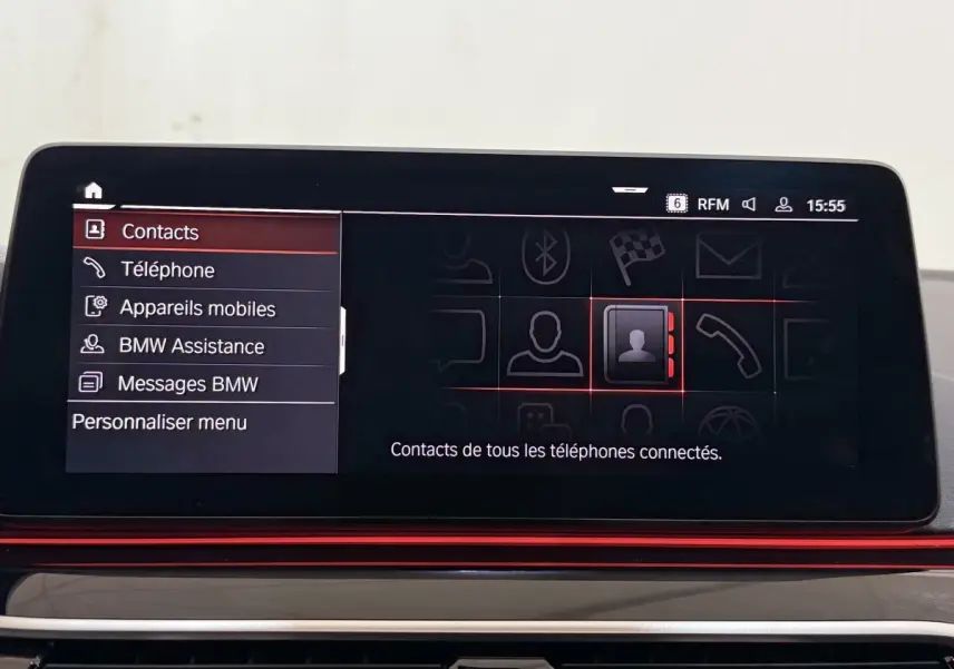Écran tactile central de la BMW Série 5 Touring 520d M Sport 2023 affichant le menu contacts en intérieur noir et rouge.