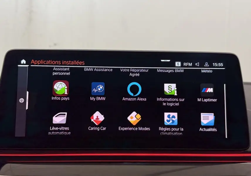 Écran tactile central affichant les applications connectées dans l’habitacle d’une BMW Série 5 Touring noire, vue de face.