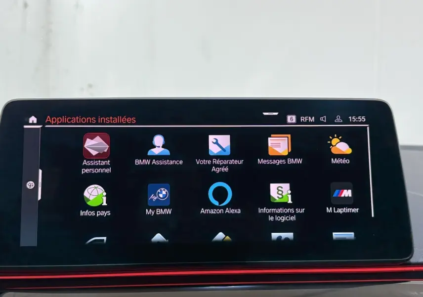 Écran tactile central affichant les applications installées dans une BMW Série 5 Touring noire, vue intérieure.