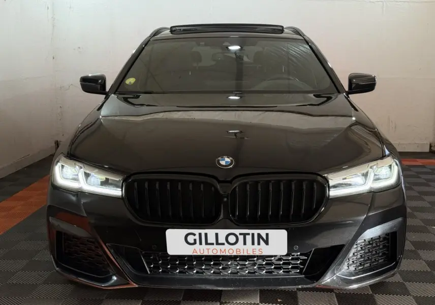 Vue frontale d'une BMW Série 5 Touring 520d noire avec phares LED allumés et calandre noire M Sport.