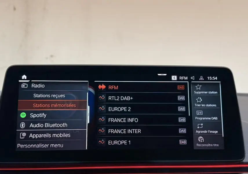 Écran tactile central de BMW Série 5 Touring 520d M Sport 2023 affichant les stations radio en mode DAB.
