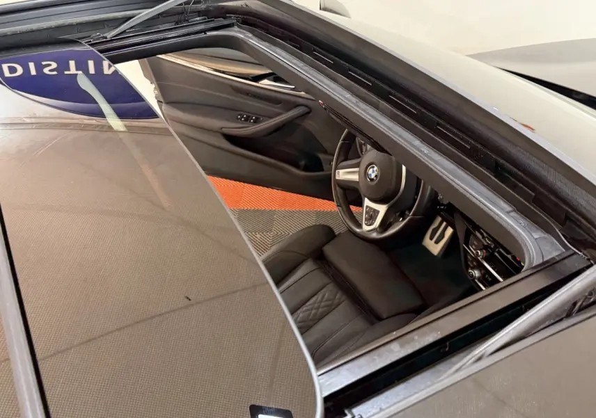 Vue plongeante sur l'intérieur noir de la BMW Série 5 Touring 520d M Sport 2023, avec toit ouvrant ouvert.