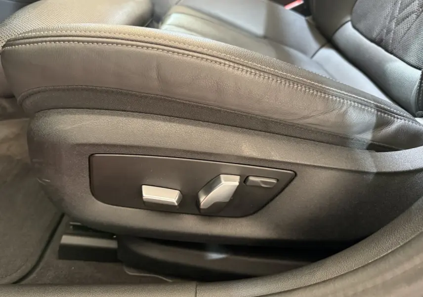 Gros plan sur les commandes de réglage électrique du siège avant en cuir noir d'une BMW Série 5 Touring 520d M Sport.