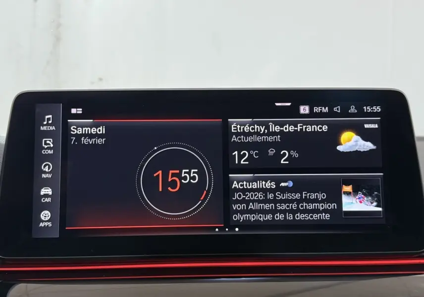 Écran tactile central de la BMW Série 5 Touring 520d M Sport 2023 affichant l'heure, météo et actualités.