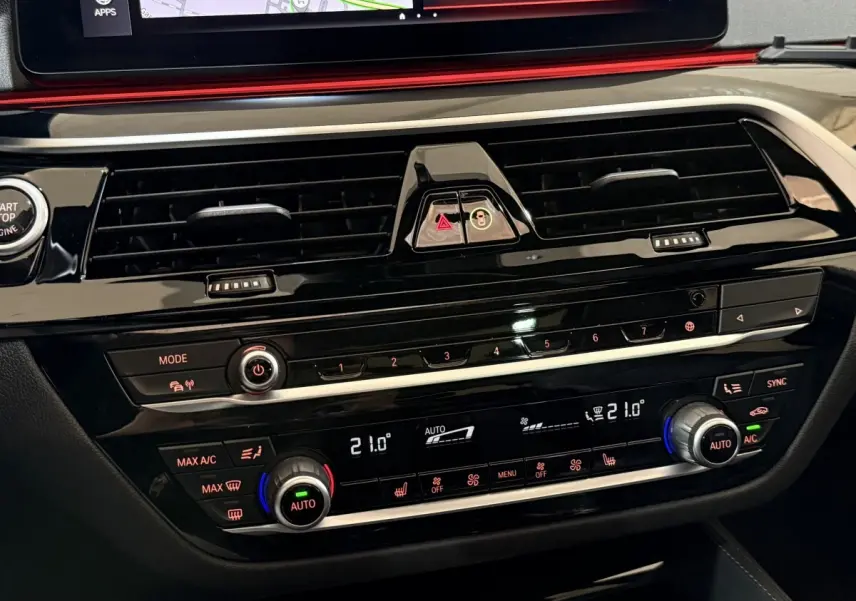 Gros plan sur la console centrale noire brillante de la BMW Série 5 Touring 520d, avec commandes climatisation digitale et écran tactile.