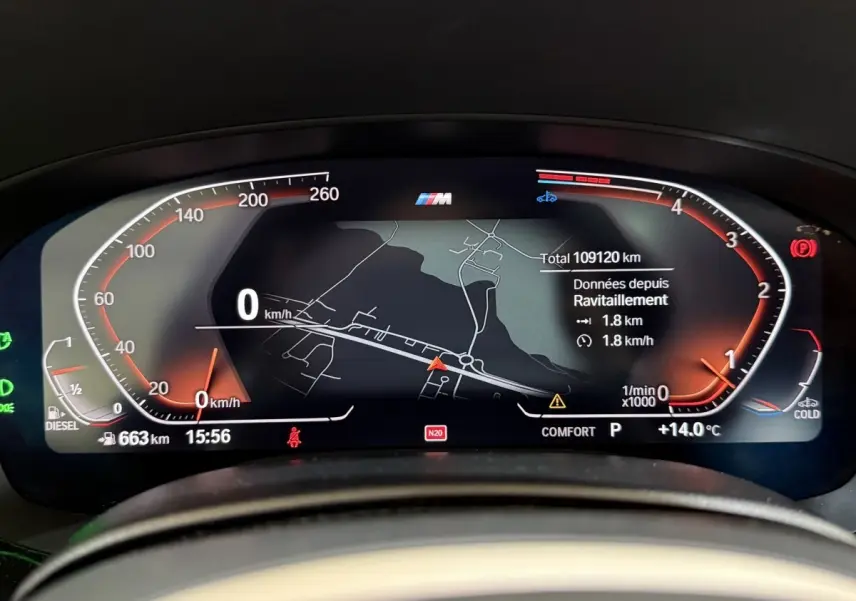 Affichage numérique du combiné d'instruments BMW Série 5 Touring 520d, avec navigation et compteurs rouges sur fond noir.
