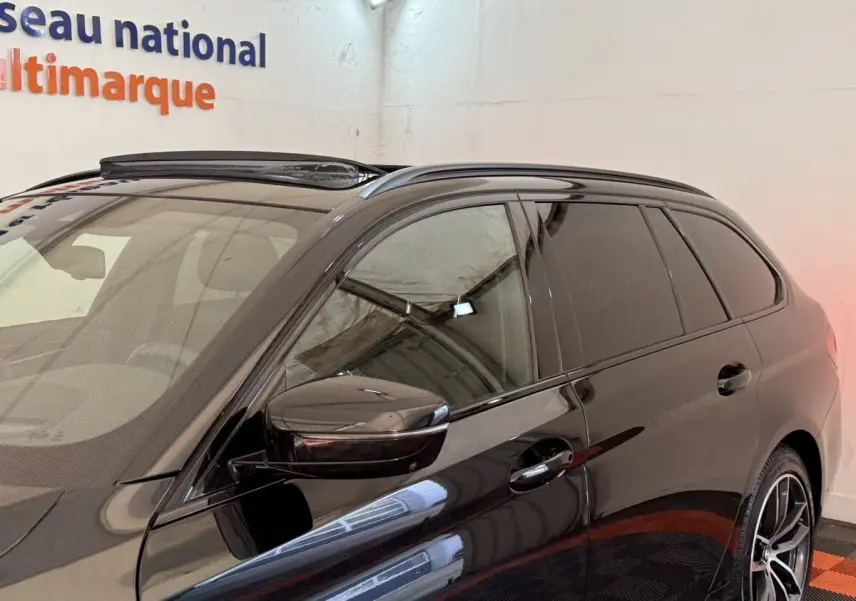 Vue de côté droit avant d'une BMW Série 5 Touring 520d noire avec vitres teintées et rétroviseur assorti.