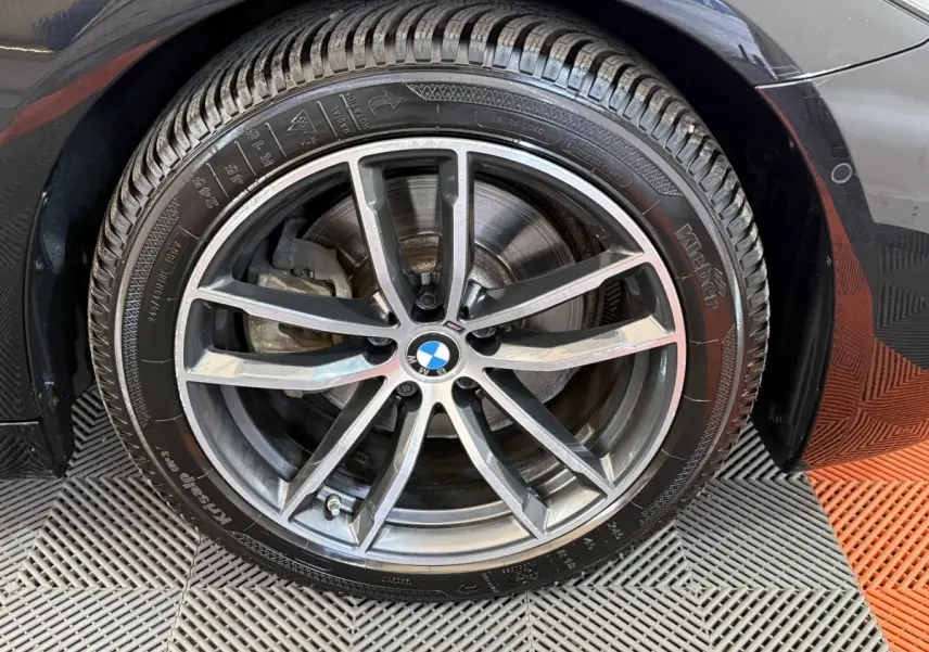 Gros plan sur la roue avant droite noire d’une BMW Série 5 Touring 520d M Sport avec jante alliage à 5 doubles branches.