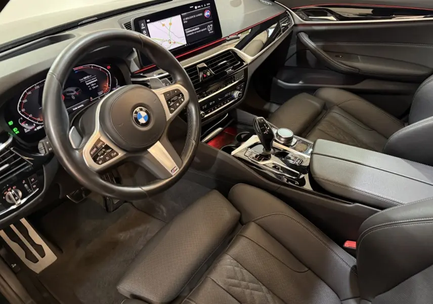 Vue intérieure côté conducteur de la BMW Série 5 Touring 520d M Sport 2023 avec tableau de bord digital et cuir noir.