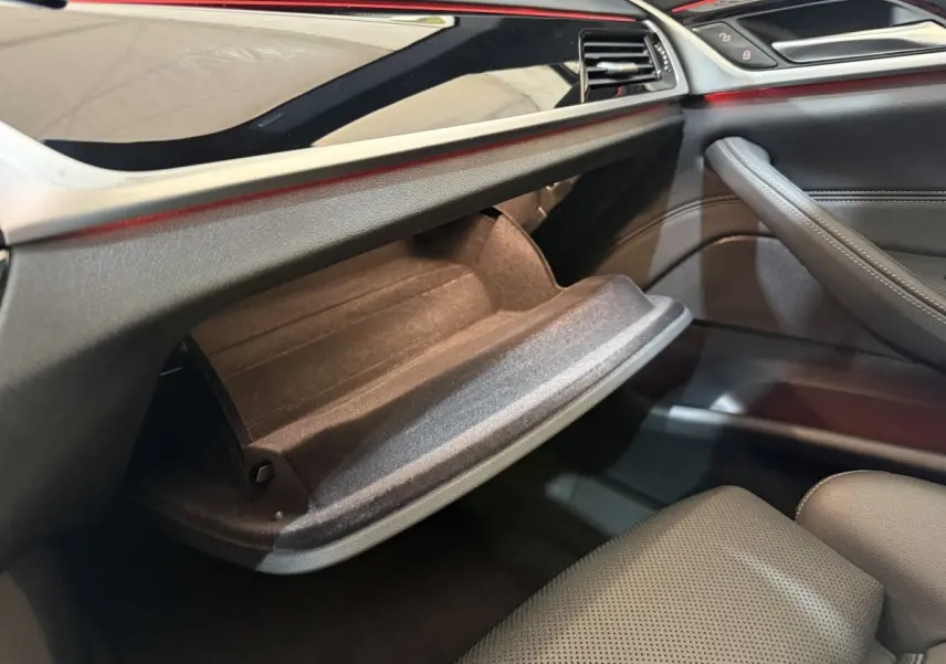 Vue intérieure côté passager de la BMW Série 5 Touring 520d M Sport 2023, boîte à gants ouverte et garniture noire.