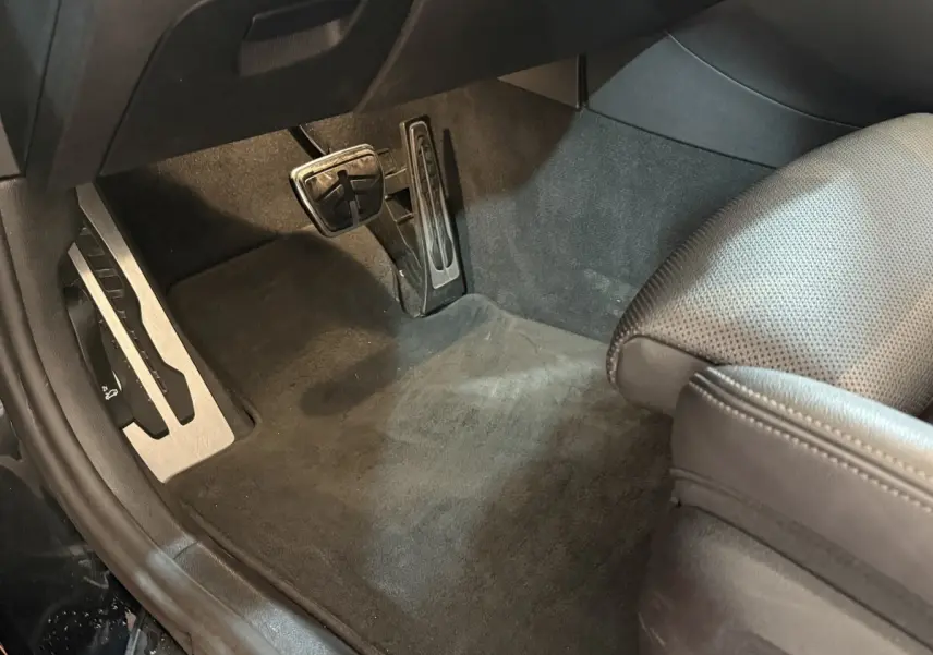 Vue rapprochée des pédales et du tapis noir côté conducteur de la BMW Série 5 Touring 520d M Sport 2023.