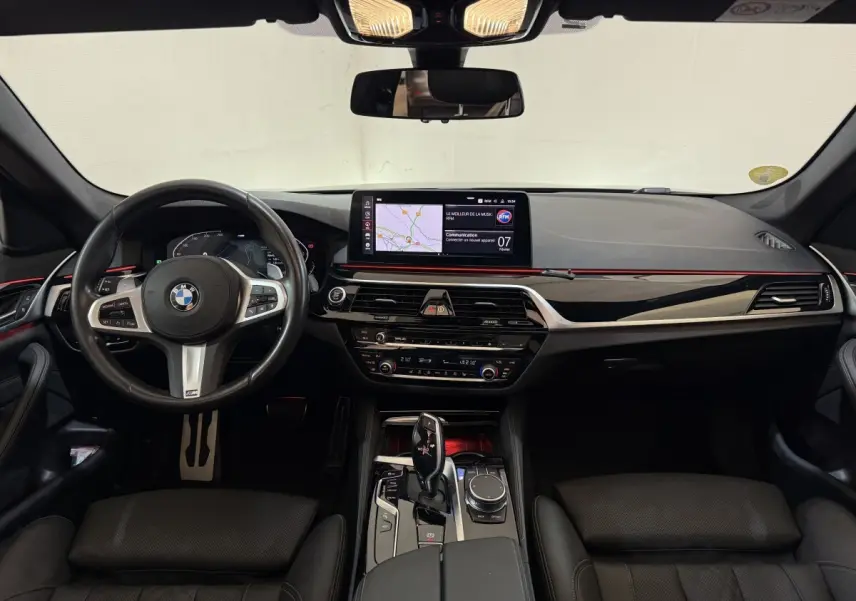 Vue frontale de l'intérieur noir de la BMW Série 5 Touring 520d M Sport 2023 avec écran tactile et volant multifonctions.