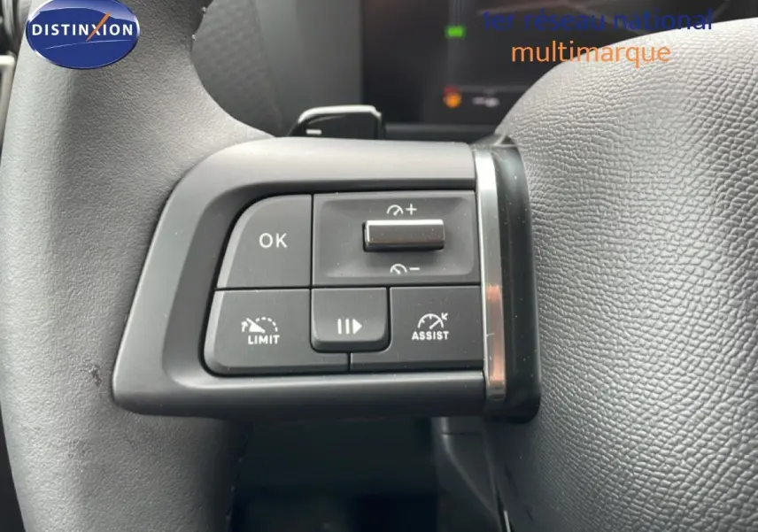Gros plan sur les commandes au volant côté gauche d'une Citroën C4 blanc métal, version PureTech 130ch automatique.