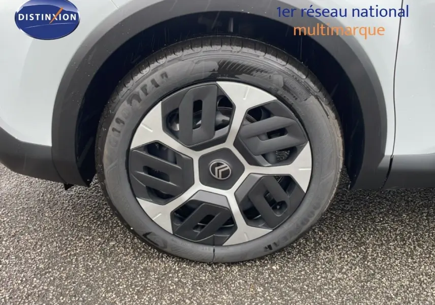 Gros plan sur la roue avant droite d'une Citroën C4 blanc métal, avec jante au design moderne bicolore noir et argent.