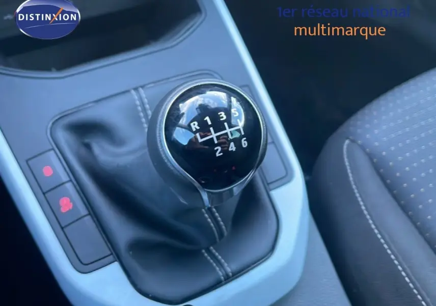 Le levier de vitesse manuel noir avec marquages blancs dans l'habitacle d'une SEAT Arona 2025, siège tissu visible.