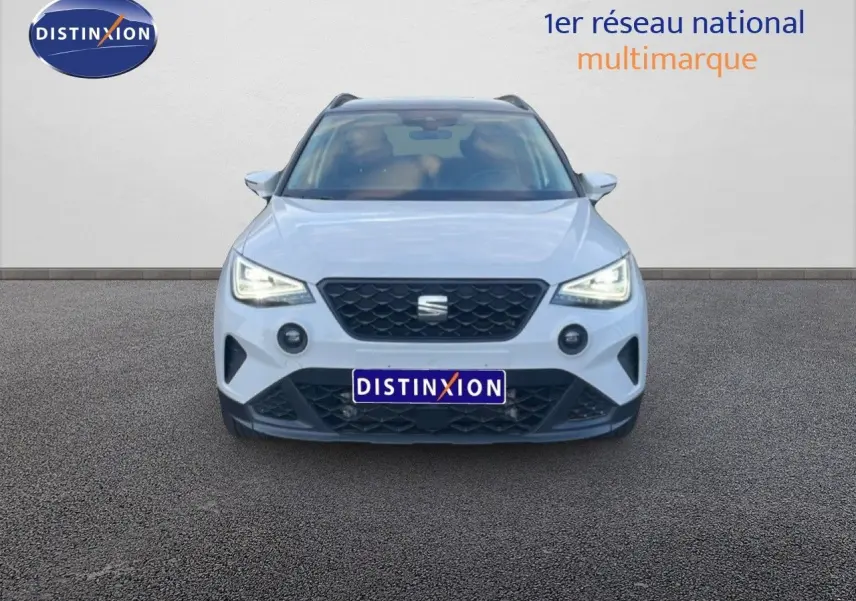 Vue frontale d'un SEAT Arona blanc avec toit gris, phares LED allumés sur fond neutre.