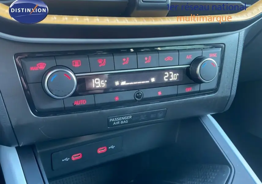 Gros plan sur la console centrale du SEAT Arona 2025, montrant la climatisation digitale et les ports USB rouges.