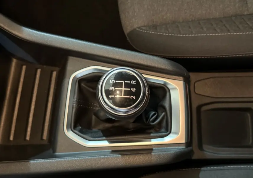 Gros plan sur le levier de vitesses manuel noir avec marquages blancs, entouré de garniture argentée dans l’habitacle.