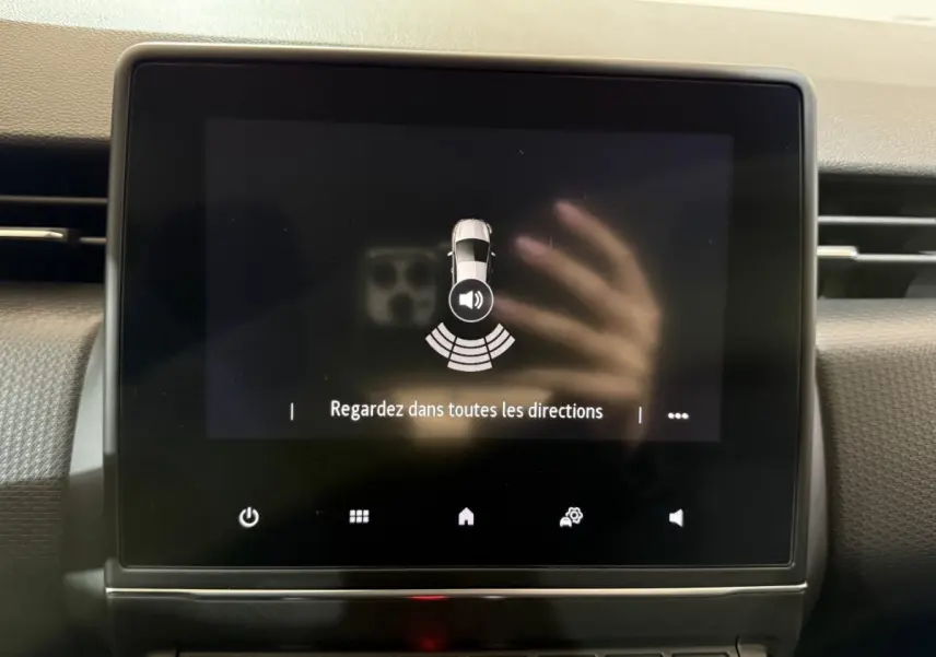 Écran tactile central de la Renault Clio Business blanc montrant l'alerte de détection de proximité au stationnement.