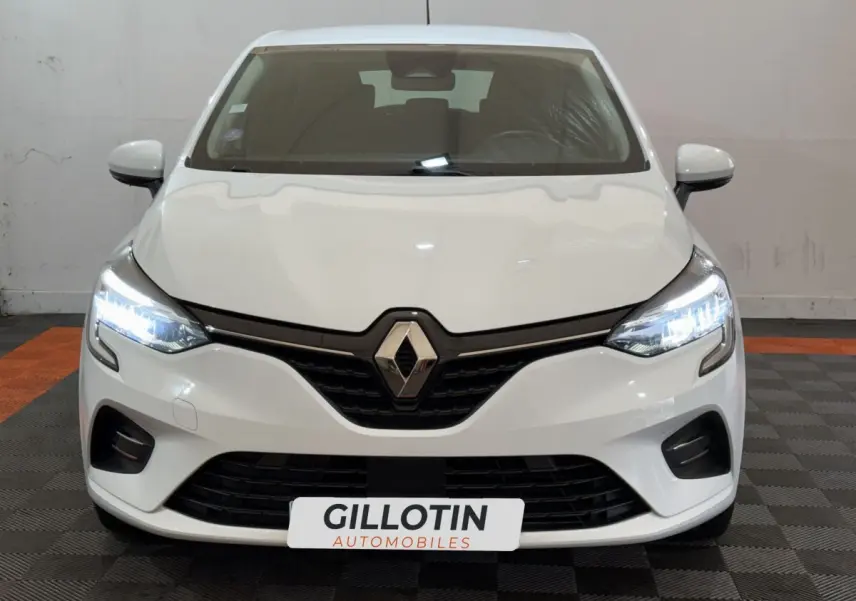 Vue frontale d'une Renault Clio Business SCe 75 blanche avec phares LED allumés et calandre noire distinctive.