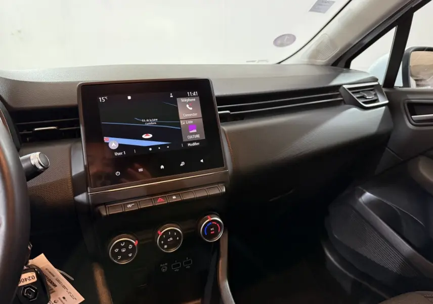 Vue intérieure côté passager de la Renault Clio Business blanche de 2020, avec écran tactile central et commandes de climatisation.