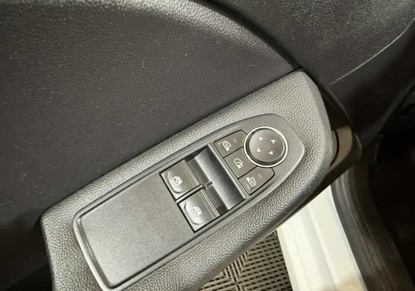 Gros plan sur la commande des vitres électriques côté conducteur d’une Renault Clio Business blanche, intérieur noir.