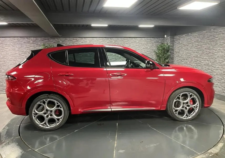 Vue profil droit d'un Alfa Romeo Tonale rouge 2024 avec jantes alliage 20 pouces et étriers de frein rouges visibles.