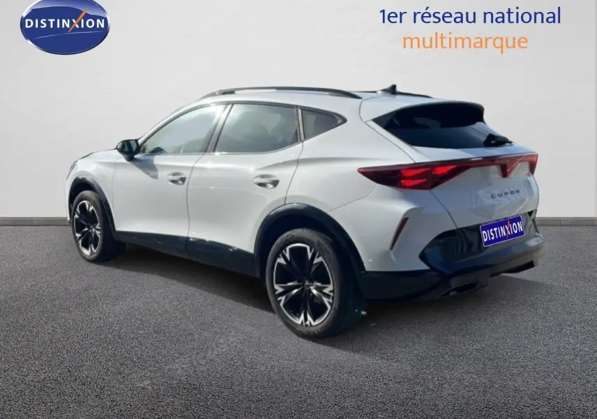 Vue 3/4 arrière droite d’un CUPRA Formentor blanc neige métal avec jantes noires bicolores et toit noir.