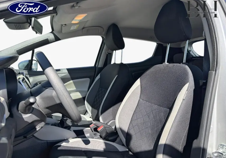 Vue intérieure côté conducteur d'une Nissan Micra 2017 avec sièges tissu noir et gris, volant multifonction et boîte manuelle.