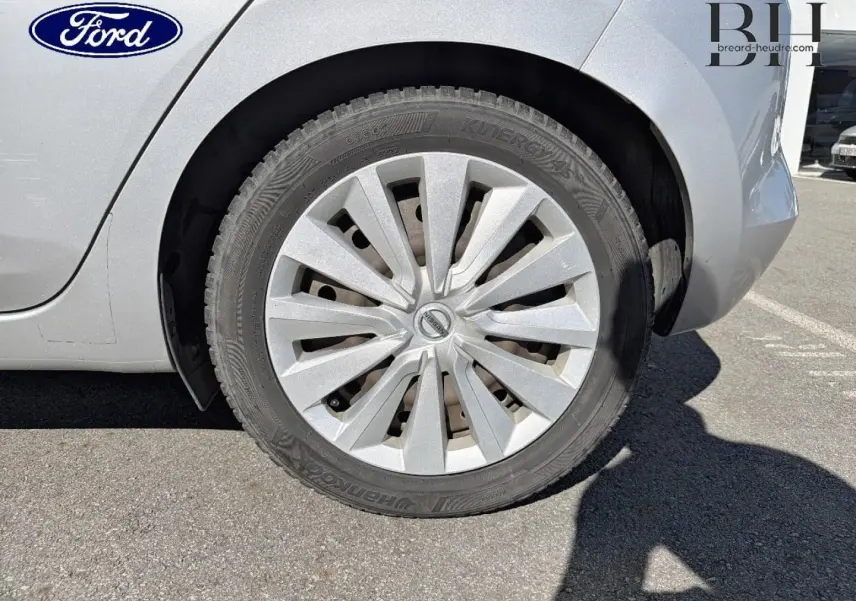 Gros plan sur la roue arrière droite argentée d'une Nissan Micra 2017, avec enjoliveur et carrosserie grise visible.