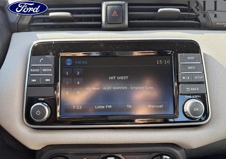 Tableau de bord beige avec écran tactile central et commandes média, intérieur d'une Nissan Micra vue de face.