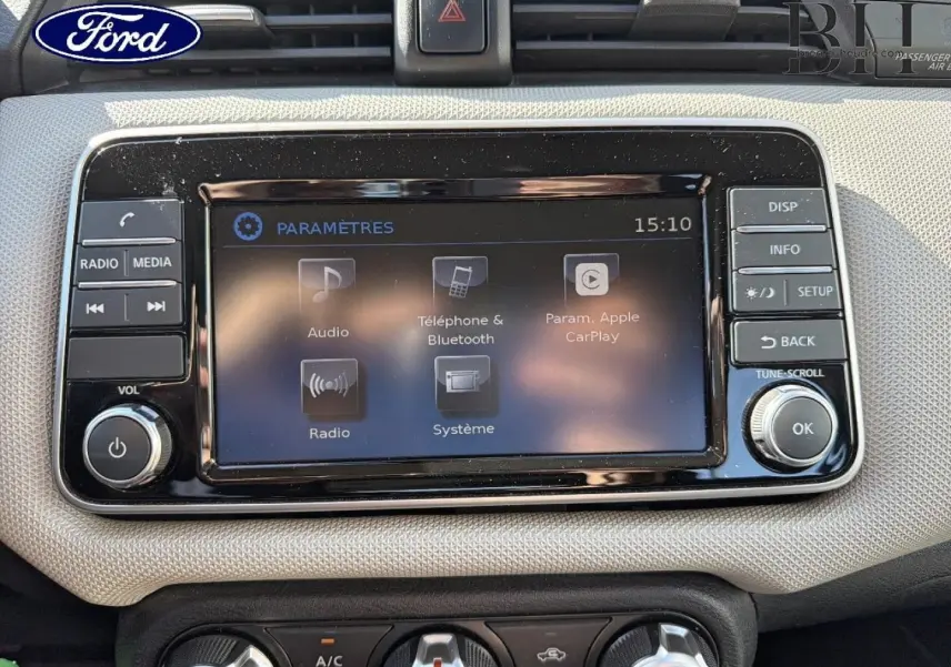 Écran tactile central noir avec commandes autour, tableau de bord beige clair de Nissan Micra 2017, vue frontale rapprochée.