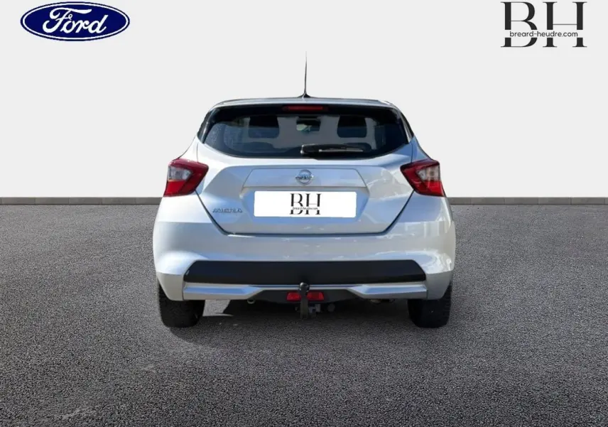 Vue arrière d'une Nissan Micra blanche 2017 avec attelage et feux arrière rouges sur fond neutre.