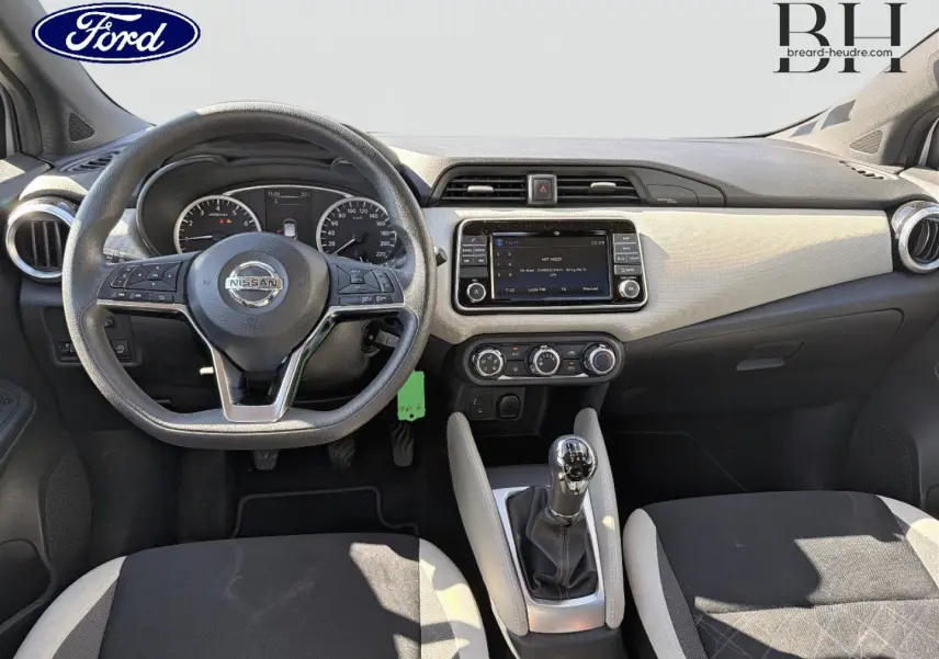 Vue intérieure avant centrée sur le tableau de bord et volant Nissan d'une Micra 2017, avec levier de vitesse manuel et sellerie bicolore.