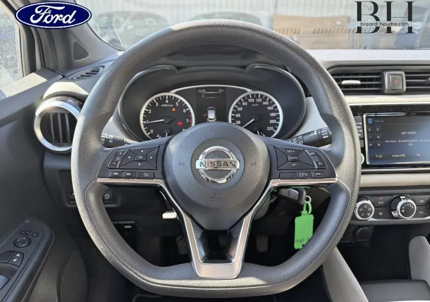 Vue intérieure centrée sur le volant Nissan Micra 2017, tableau de bord et écran tactile visibles en arrière-plan.