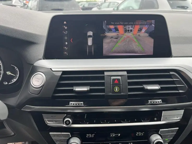 Vue intérieure du tableau de bord de la BMW X3 xDrive30e 2020 avec écran de caméra de recul affiché.
