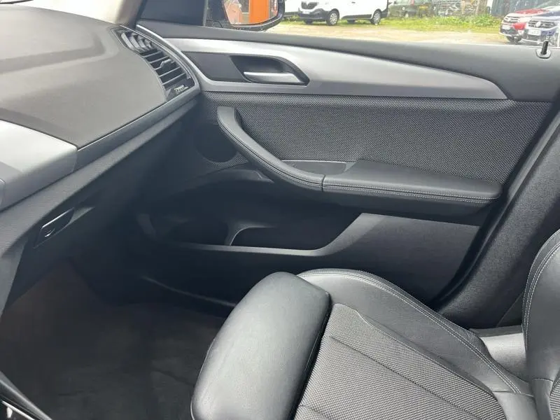 Vue intérieure côté passager de la BMW X3 xDrive30e 2020 avec sellerie tissu anthracite et garnitures noires.