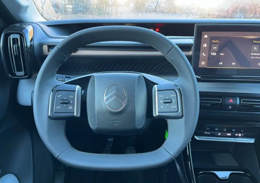 Vue intérieure centrée sur le volant cuir multifonctions et l’écran tactile du tableau de bord du Citroën C3 Aircross noir.