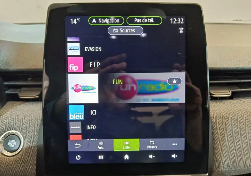 Écran tactile central de la Renault Clio Techno TCe 90 2024 affichant les stations radio, avec bouton démarrage visible à gauche.