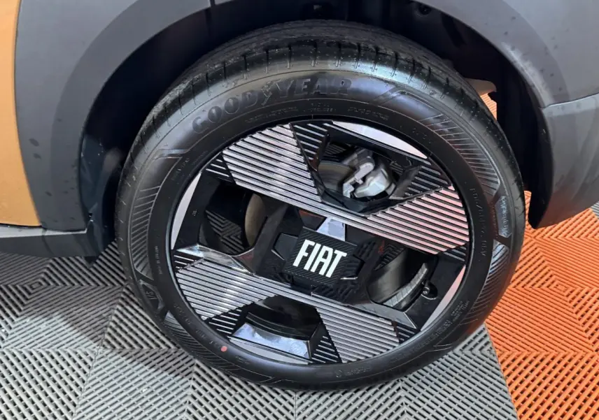 Gros plan sur la roue avant gauche marron du FIAT Grande Panda 1.2 Hybrid avec jante noire et détails argentés.