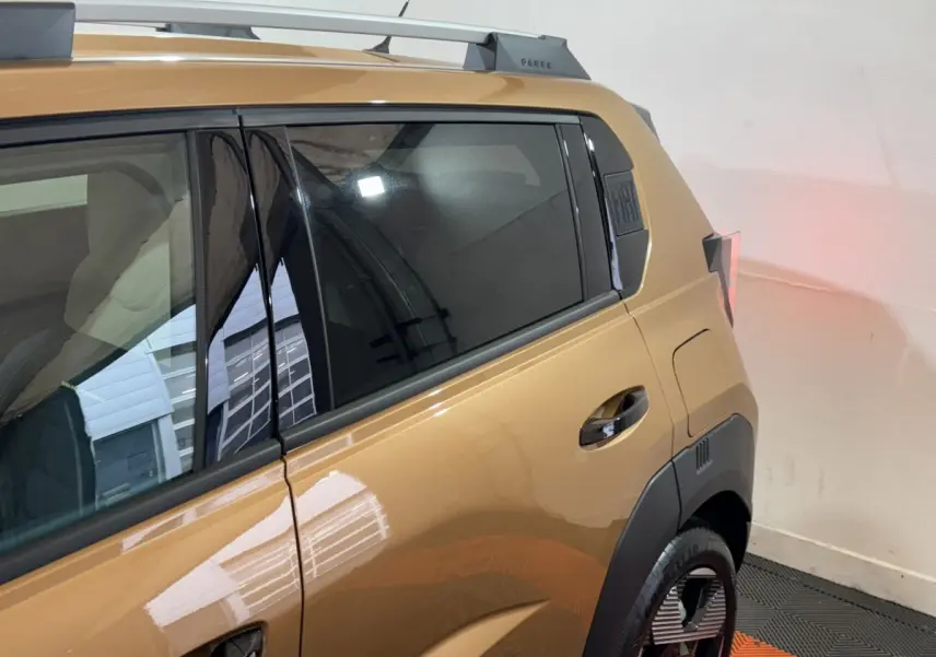 Vue latérale arrière droite d'une FIAT Grande Panda marron 2025 avec vitres teintées et barres de toit chromées.