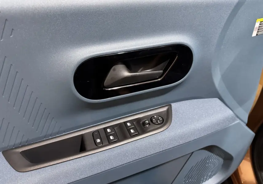 Gros plan sur la porte côté conducteur marron de la Fiat Grande Panda avec poignée noire et commandes électriques.